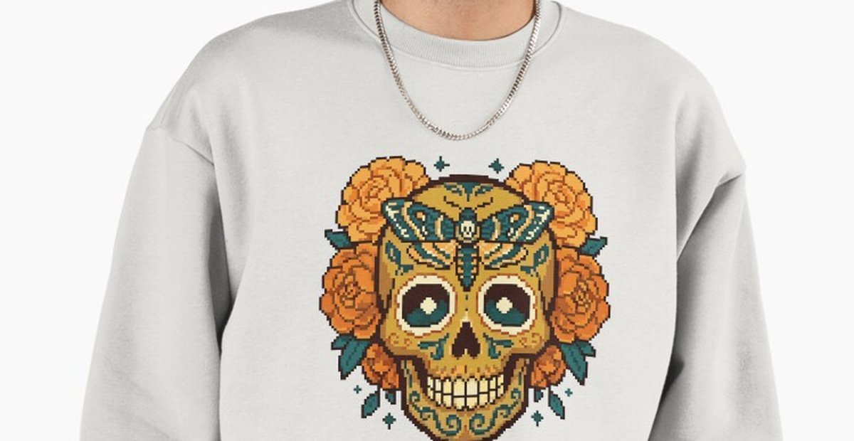 Golden sugar skull calavera pixel art design with a teal moth and marigolds, printed on a cream sweatshirt.